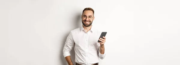 Schöner Manager Mit Smartphone Und Zufrieden Lächelnd Sms Sendend Vor — Stockfoto