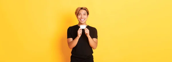 Ενθουσιασμένος Χαρούμενος Ασιάτης Χαμογελάει Και Δείχνει Πιστωτική Κάρτα Στέκεται Κίτρινο — Φωτογραφία Αρχείου