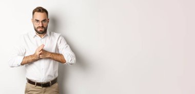 Kızgın adam parmak eklemlerini kırıyor, birini yumruklamak istiyor, beyaz arka plana karşı kızgın duruyor..