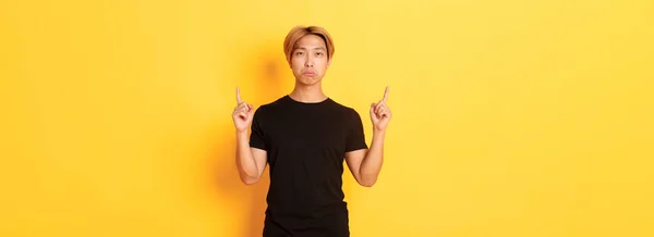 Portrét Trucujícího Zachmuřeného Asijského Chlapa Zklamaný Ukazující Prsty Nahoru Žluté — Stock fotografie