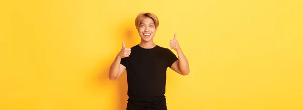 満足したアジアの男の肖像笑顔と上の親指アップ黄色の背景 — ストック写真
