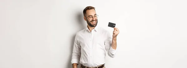 Yakışıklı Adamı Kredi Kartını Gösteriyor Tatmin Olmuş Görünüyor Beyaz Arka — Stok fotoğraf