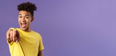 Neşeli, şaşkın, korkusuz bir İspanyol 'un yakın plan portresi. Genç öğrenci kamerayı gösterip gülüyor. Tanıdık, mor arka planda duran birini tanıyor..