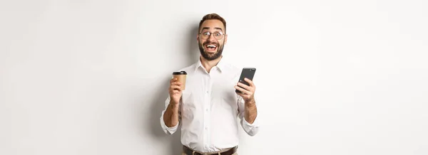 사업가가 커피를 마시고 핸드폰으로 온라인 제공에 반응하고 백지를 배경으로 — 스톡 사진