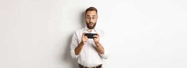 Man Ser Förvånad Mobiltelefon Står Mot Vit Bakgrund — Stockfoto