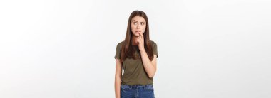 Gri arka planda yalnız duran mutlu ve şaşırmış genç bir bayan portresi. Kamera işaret ediyor