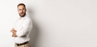 Kafası karışmış yönetici kameraya bakıyor, beyaz arkaplana karşı şokta..