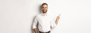 Kendine güvenen işadamı, beyaz arka planda duran şirket logosunu işaret ediyor..