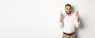 Endişeli bir adam dilek diliyor, dua ediyor ve zevk için umut ediyor, beyaz arka planda duruyor..