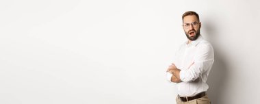 Kafası karışmış yönetici kameraya bakıyor, beyaz arkaplana karşı şokta..