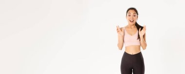 Spor, refah ve aktif yaşam tarzı konsepti. Mutlu coşkulu fitness kızı, Asyalı sporcu kadın fantastik haberlerden ellerini sıkan, nefes nefese kalmış, beyaz arka planda duran.