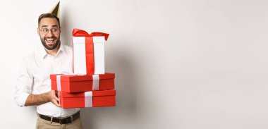 Tatiller ve kutlamalar. Heyecanlı bir adam doğum günü partisi veriyor, hediyeler alıyor, mutlu görünüyor, beyaz arka planda duruyor..