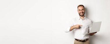 İş için. Dizüstü bilgisayarda çalışan yakışıklı bir yönetici, bilgisayara bakıyor ve gülümsüyor..