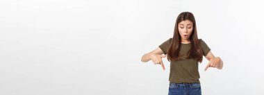 Gri arka planda yalnız duran mutlu ve şaşırmış genç bir bayan portresi. Kamera işaret ediyor