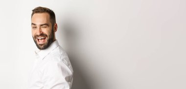 Sakallı küstah adamın yakın çekimi, kameraya dön ve gülümseyerek göz kırp, beyaz arka planda dur..