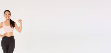 Spor ve bacaklı, kendinden emin gülümseyen Asyalı bayan sporcu, kendini gösteren fitness kızı, aktif ve sağlıklı bir yaşam tarzı, profesyonel olmak, beyaz arka planda durmak..