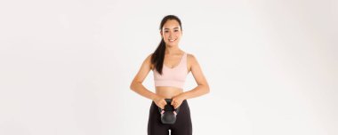 Spor, refah ve aktif yaşam tarzı konsepti. Güçlü ve zayıf Asyalı fitness kızı, vücut geliştirme, spor aletleri, kettlebell egzersizi, beyaz arka plan.