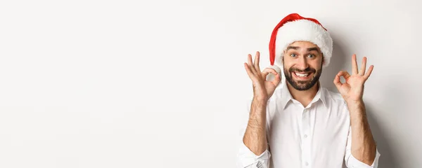 パーティー 冬の休日やお祝いの概念 喜びの男はクリスマスを楽しんで 良い兆候を示し 満足笑顔 サンタの帽子を身に着けて 白い背景 — ストック写真