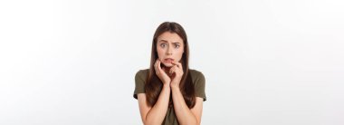 Dili tutulmuş, şok olmuş ve kızgın bir kadın, sessizliğini ve yanlış anlaşılmalarını ifade ediyor, korkmuş. Gri arkaplan üzerinde izole.