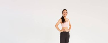 Tam uzunlukta terli, gülümseyen fitness kızı, aktif giyinen bayan sporcu spor yaparken mutlu görünüyor, spor salonunda antrenman yapıyor, egzersizlerden memnun, koç mükemmel vücut elde etmeye yardım ediyor, beyaz arka plan..