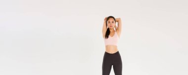 Tam boy odaklanmış ve motive olmuş Asyalı bayan sporcu, esmer fitness kızı esneme egzersizleri yaparken kararlı görünüyor, antrenmandan önce ısınma egzersizleri, el ele tutuşmalar....