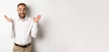 Şaşırmış mutlu erkek girişimci el çırpıyor ve gülümsüyor, kameraya bakıyor, beyaz arka planda duruyor..