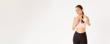 Spor, refah ve aktif yaşam tarzı konsepti. Aktif giyimli, isteksiz ve hoşnutsuz Asyalı bayan sporcu reddedilmiş, suratını buruşturmuş ve iğrenç bir şeye sinmiş, reddedilmiş..