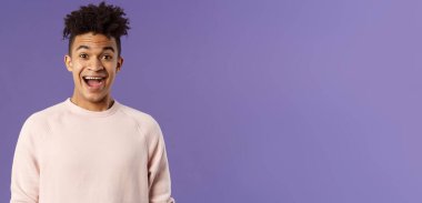 Hevesli, heyecanlı ve şaşırmış İspanyol adamın yakın plan portresi inanılmaz haberler duyuyor, şaşkınlık ve sevinçten ağzı açık gülümsüyor, arkadaşının başarısına seviniyor, mor arka plan.