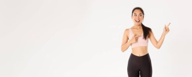 Spor, refah ve aktif yaşam tarzı konsepti. Heyecanlı, ince ve tatlı Asyalı fitness kızı, sağ üst köşeyi gösteren bayan sporcu, spor malzemeleri satış promosyonu ya da spor salonu teklifi gösteriyor..