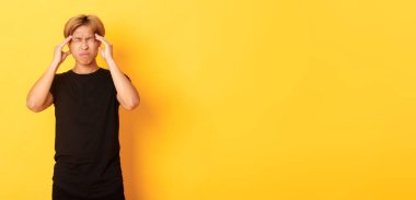 Sorunlu Asyalı erkek öğrencinin portresi. Baş ağrısı, ekşitme, baş ağrısı, migren ağrısı..