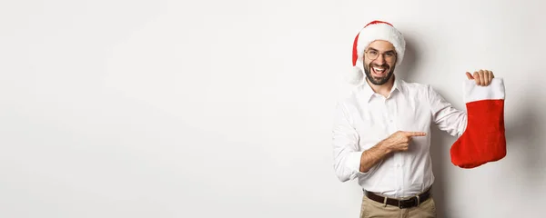 Gelukkig Man Santa Hoed Vieren Wintervakantie Wijzen Naar Kerstsok Glimlachen — Stockfoto