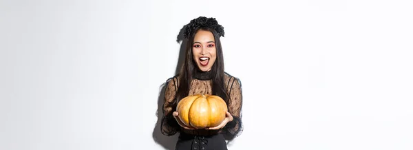 魔女の衣装で楽しいアジアの女性のイメージ ハロウィンを祝います あなたにカボチャを与え 怖い見て 白い背景の上に立って — ストック写真