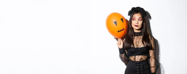 穿着巫婆服装的愚蠢的美丽的亚洲女人的形象 带着可怕的脸的橙色气球 庆祝万圣节 — 图库照片