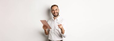 Mutlu ve memnun patron iyi bir iş çıkardı, dijital tablet okudu, kamerayı size çevirdi, beyaz arka planda durdu..