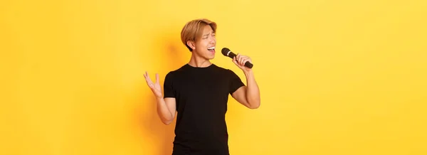 Kaygısız Yakışıklı Asyalı Koreli Şarkıcı Tutkuyla Mikrofona Şarkı Söylüyor Sarı — Stok fotoğraf