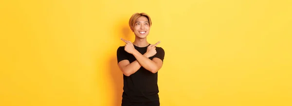 Portret Uśmiechniętego Azjaty Patrzącego Lewo Podejmującego Decyzję Wskazującego Bokiem Żółte — Zdjęcie stockowe