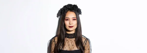 黒の花輪を持つ美しいゴシックガールのクローズアップ ハロウィンパーティーのために身を包んだ取得 邪悪な魔女の衣装で白い背景の上に立って — ストック写真