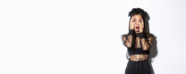 Korkmuş bir kadın resmi. Sersemlemiş ve korkunç bir şeye bakıyor. El ele tutuşmuş, cadılar bayramı kostümü giymiş..