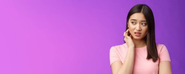 Endişeli genç ürkek Asyalı kız gergin, boynu kaşınan, tedirgin, yana bakan, tehlikeyi hisseden, üzgün, morarmış arka planda duran huzursuz.