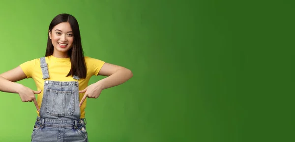 優しい発信かわいいアジアの若い女性は指を下に表示し 新しいプロモーションアプリを紹介し 喜んでリンクを共有笑顔 ブランドを使用して製品をお勧めします 歯を食いしばる 緑の背景 スペースのコピー — ストック写真