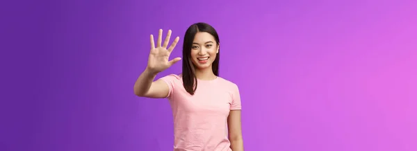 友善可爱的亚洲柔情蜜意的女孩举起手掌挥手道别 开心地微笑 高兴地欢迎朋友邀请进来 打招呼 打招呼 站在紫色的背景上 复制空间 — 图库照片
