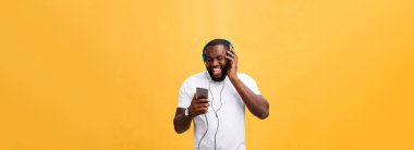 Genç Afrikalı-Amerikalı giyen kulaklık dostum ve zevk almak müzik üzerinde sarı altın arka plan.