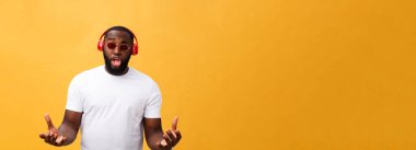 Genç Afrikalı-Amerikalı giyen kulaklık dostum ve zevk almak müzik üzerinde sarı altın arka plan.
