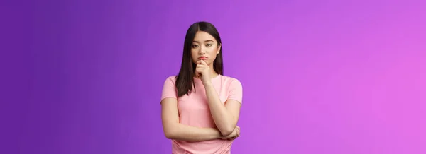 審査員の真剣な表情をしたスマートなアジアの女の子は 専門家の表情を与え 顎を思慮深く触れ 疑いを持ち 決定を下し 製品を選び 熟考し 計画を立て 紫色の背景 — ストック写真