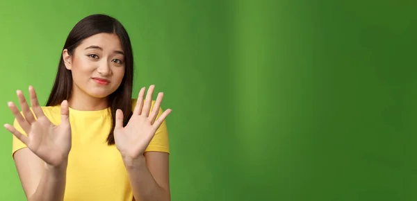 最もかわいい不安定な臆病なアジアの女の子手のジェスチャー ステップバック にこやかな嫌悪感や嫌い手を振って 提案を拒否し 提案を拒否し 緑の背景に立っている スペースのコピー — ストック写真