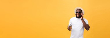 Cep telefonu ve take away kahve fincanı ile yakışıklı Afrikalı-Amerikalı. Sarı altın arka plan üzerinde izole