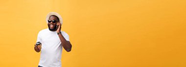 Cep telefonu ve take away kahve fincanı ile yakışıklı Afrikalı-Amerikalı. Sarı altın arka plan üzerinde izole