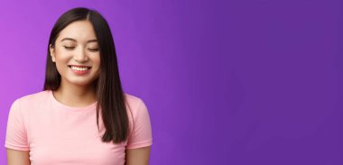 Neşeli, sevimli Asyalı kız esmer, gözlerini kapat mutlu bir şekilde gülümse, tatmin ol, iyi haberler al, hayallerin gerçek olsun, mutlu bir şekilde dur, mutluluktan sırıtarak mor arka planda dur..