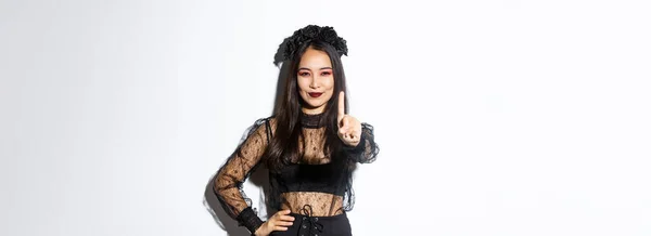 黒いゴシックのドレスとパーティーの化粧 ハロウィンのトリックや御馳走のためのドレスアップ 握手指と笑顔 停止または何かを禁止する若い美しいアジアの女性のイメージ — ストック写真