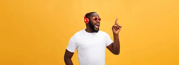 ハンサムな若いアフリカ系アメリカ人耳を傾け 自分のモバイル デバイス上の音楽を浮かべてします 黄色の背景に分離 — ストック写真